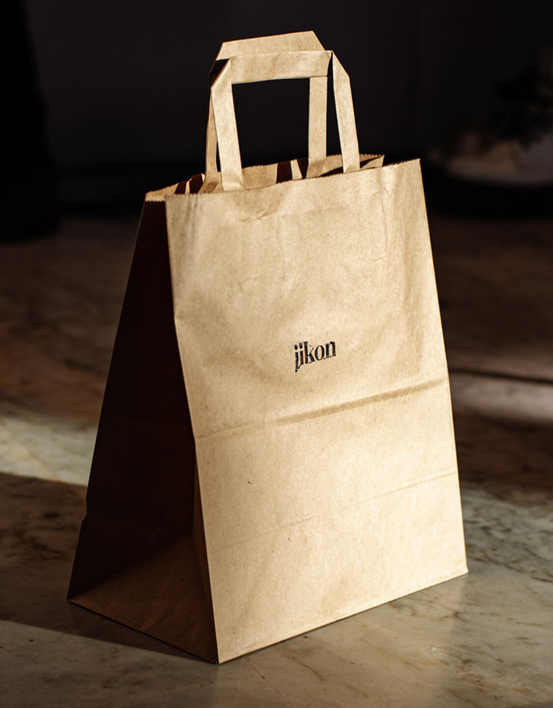 Jikon branded paper shopping bag with handles on a surface